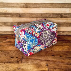 Συλλογή από χειροποίητα υφασμάτινα αξεσουάρ Terra et Ignis (Νεσεσέρ, Scrunchies, Σελιδοδείκτες) με vintage/Cottagecore μοτίβα, τοποθετημένα σε ρουστίκ επιφάνεια.